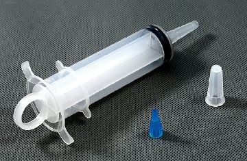 Clear plastic syringe with black plunger on a gray background